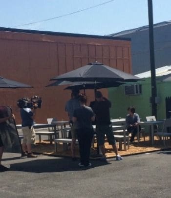 Filming scene at outdoor cafe with umbrellas.