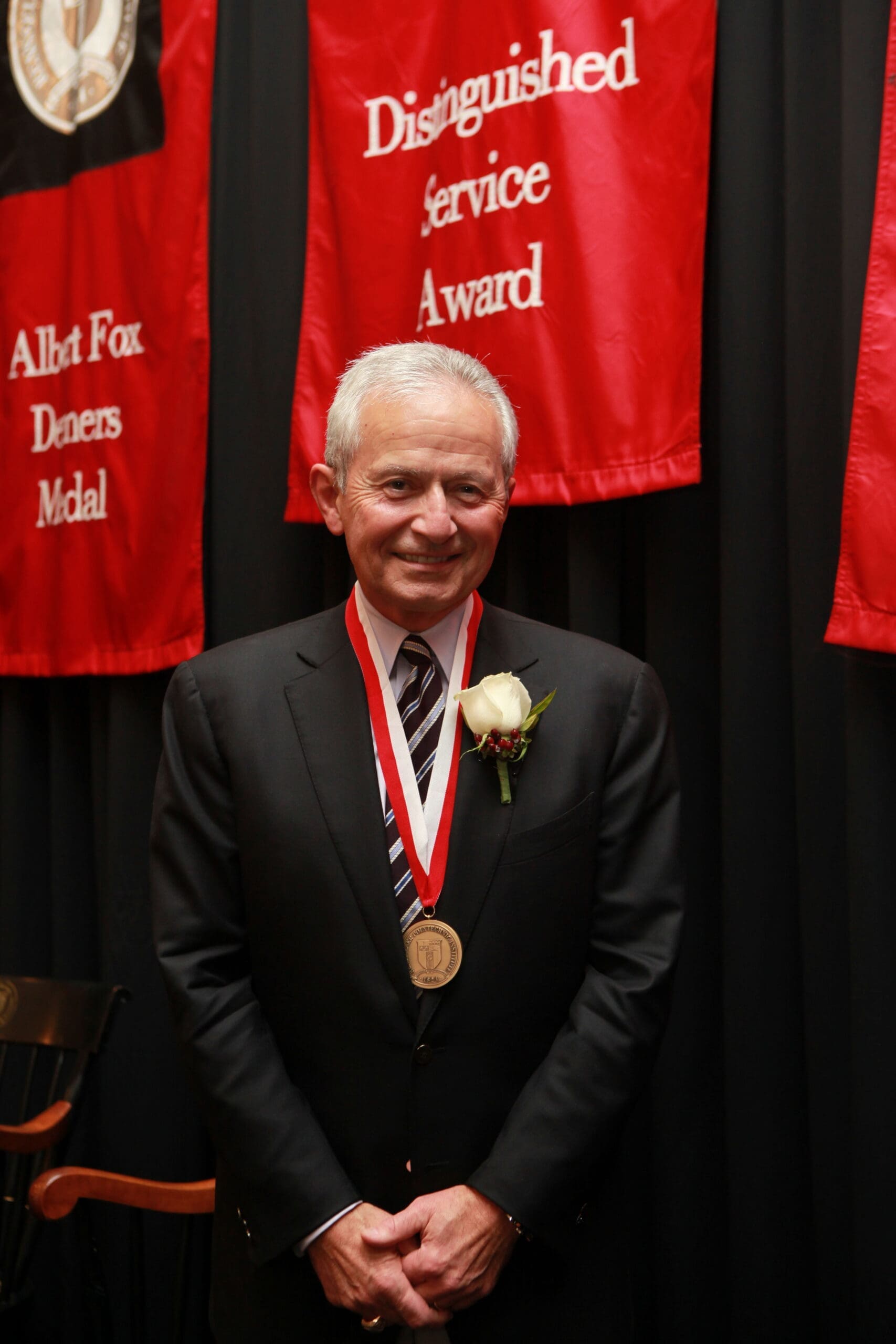 Man in suit receiving an award with red banners.