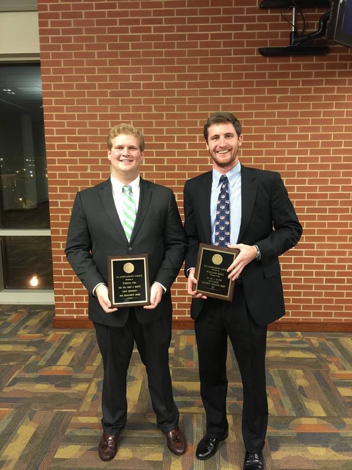 Two men holding awards at an event.