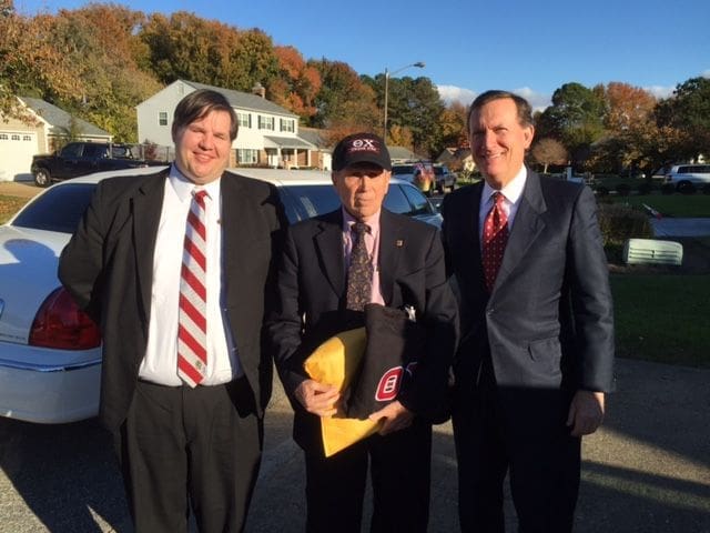 Three men posing outdoors in formal attire.