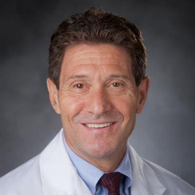 Dr. David Montefiori Smiling doctor in a white coat portrait.