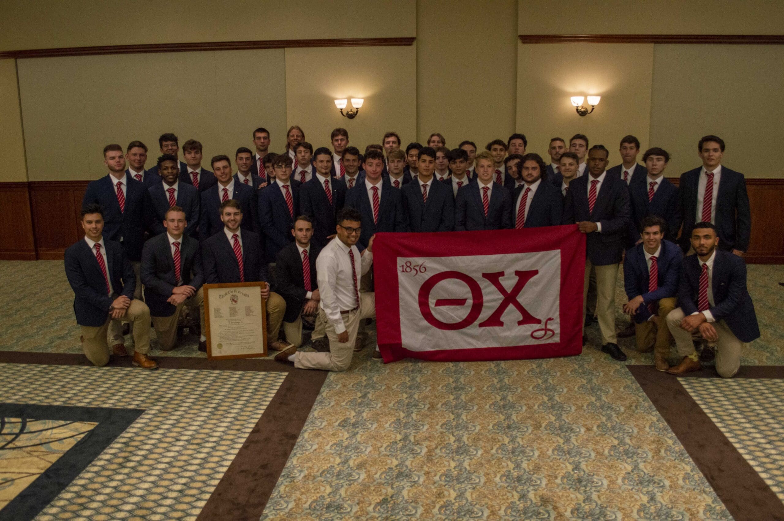 Theta Nu/Rowan Group of fraternity members posing with flag.
