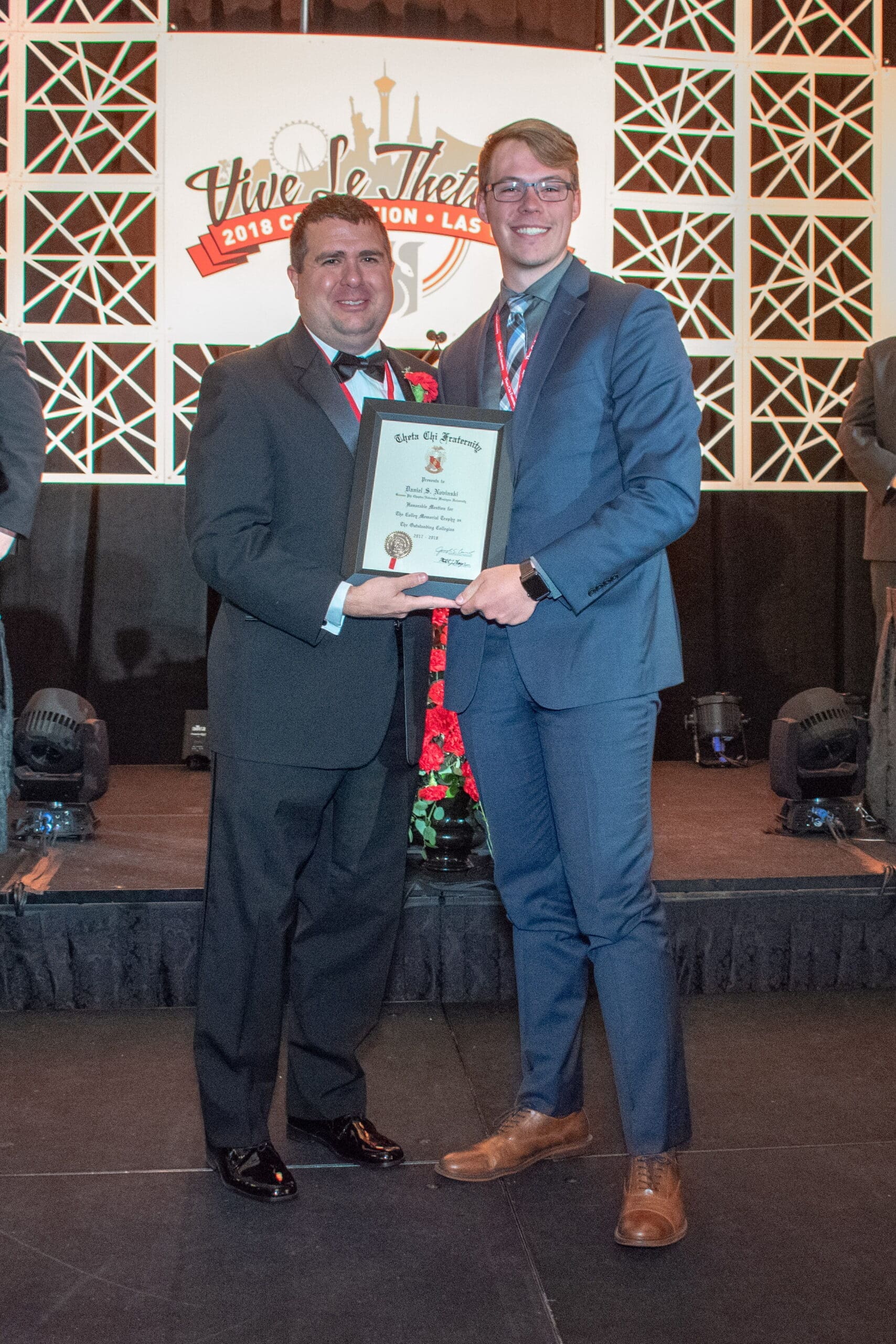 Two men receiving an award on stage.