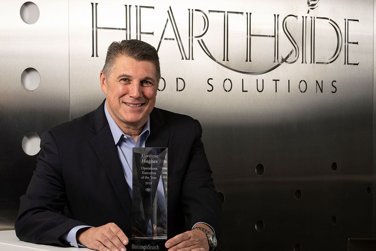 Man holding award in front of Hearthside logo.