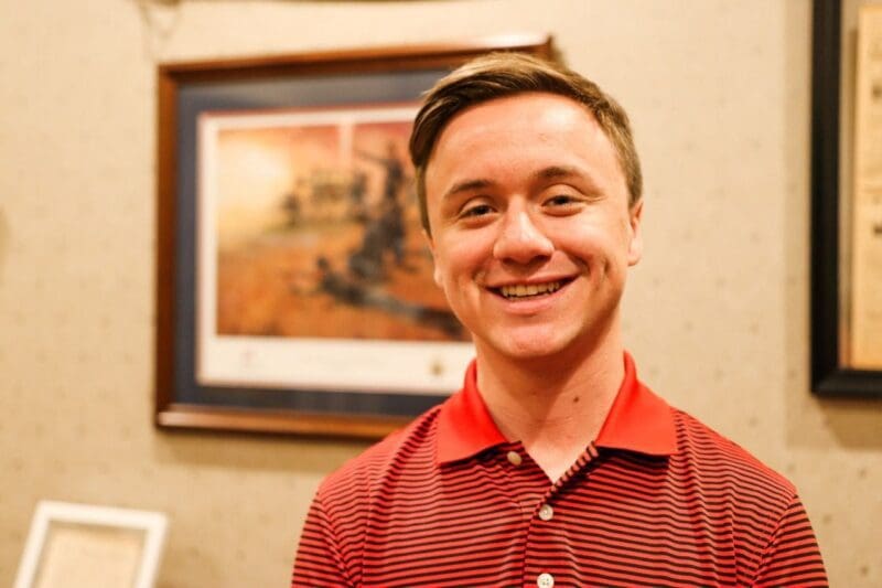Smiling young man in a red polo shirt.