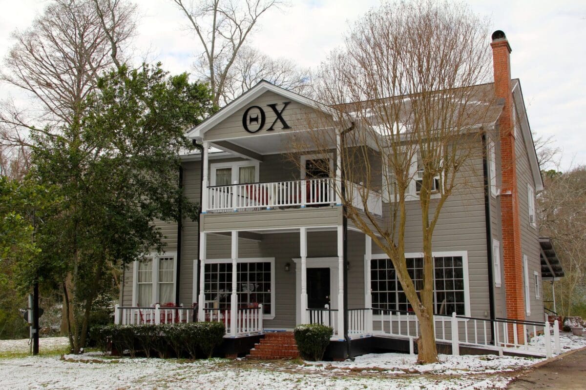 Gray house with balcony and Greek letters.