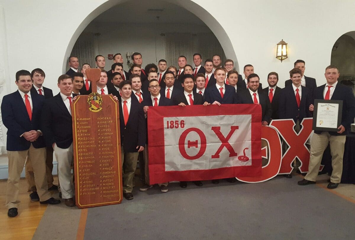 Group photo of fraternity members with banner.