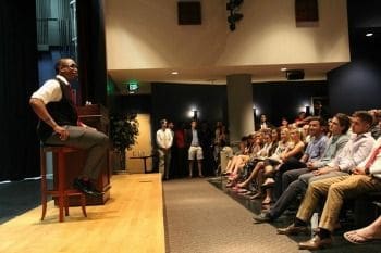 Speaker engaging audience in a lecture hall setting.
