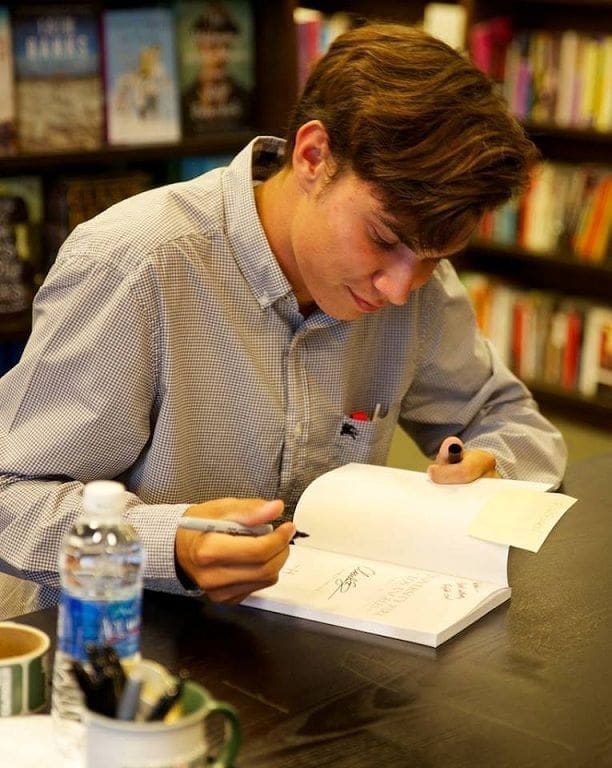 Young author signing a book in a bookstore.