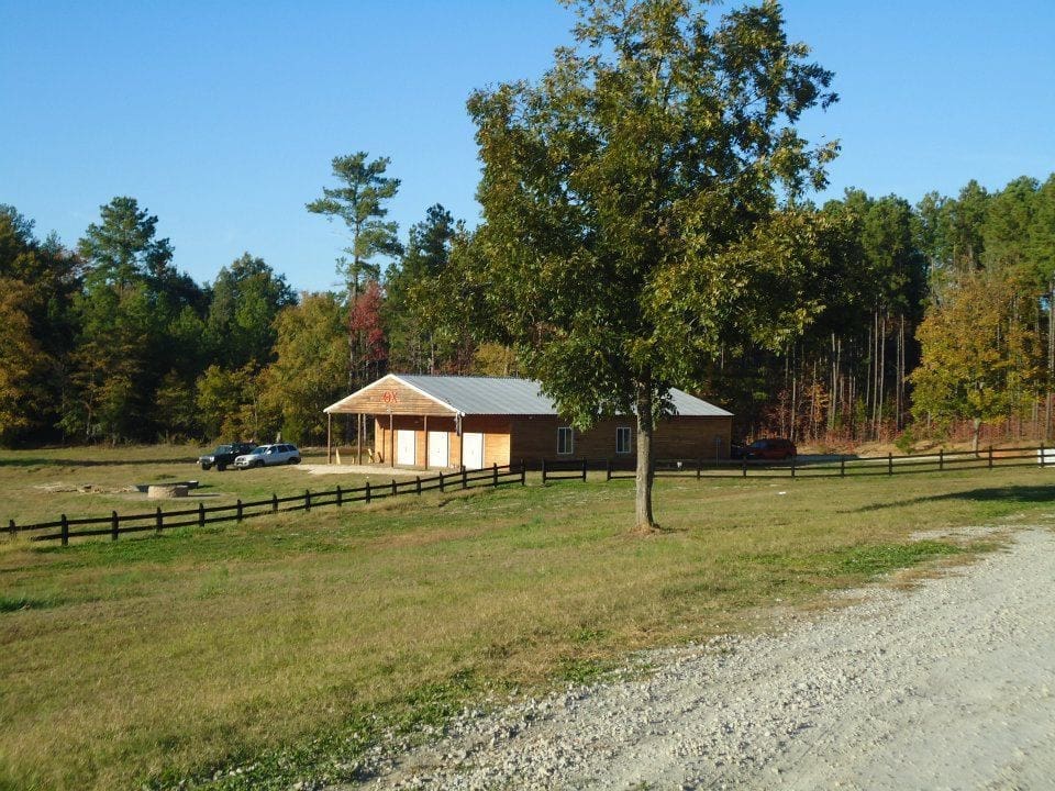 Rural house with trees and gravel driveway.