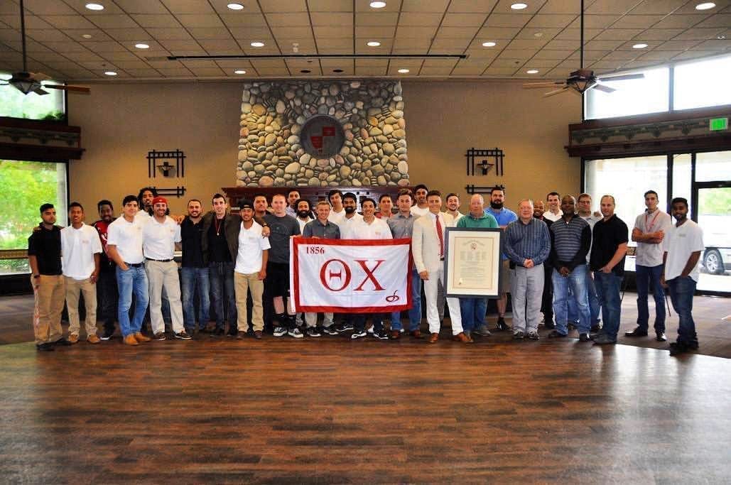 Group photo of fraternity members holding a banner.