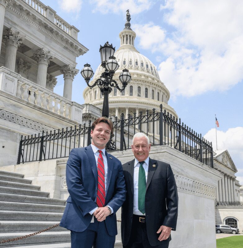 Two men posing outside the U.S. Capitol building.