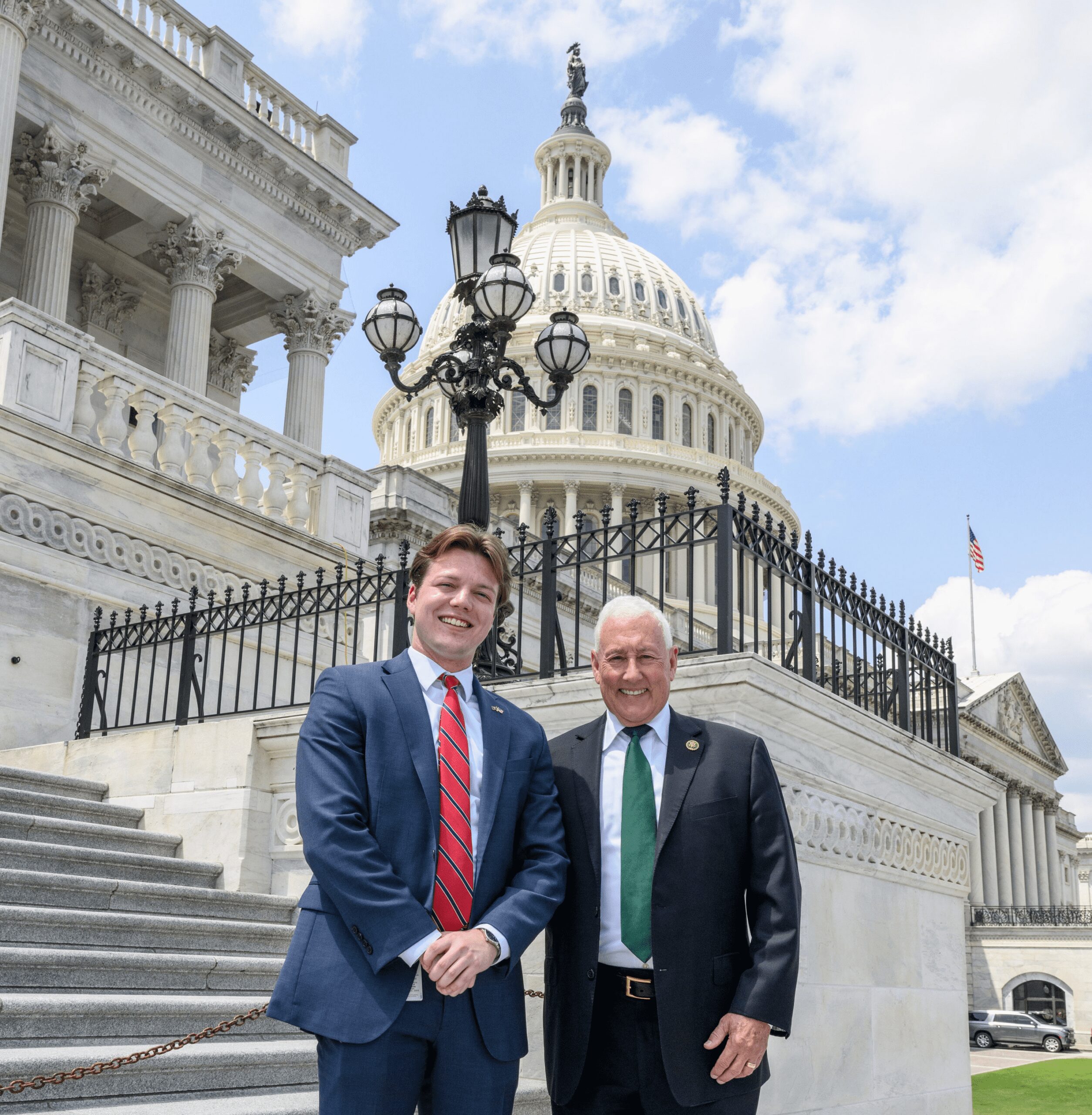 Two men posing outside the U.S. Capitol building.
