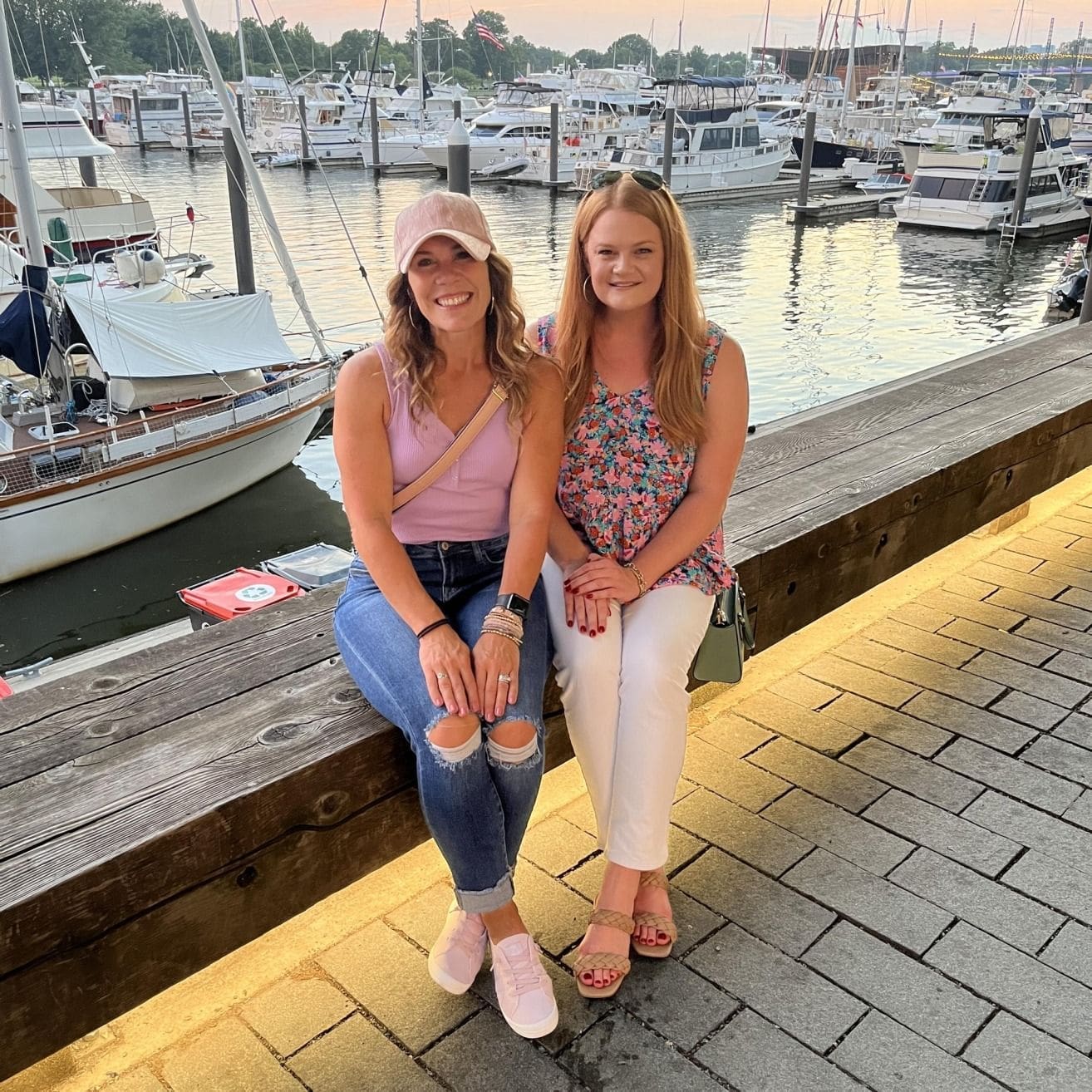 Two friends sitting by the marina at sunset.