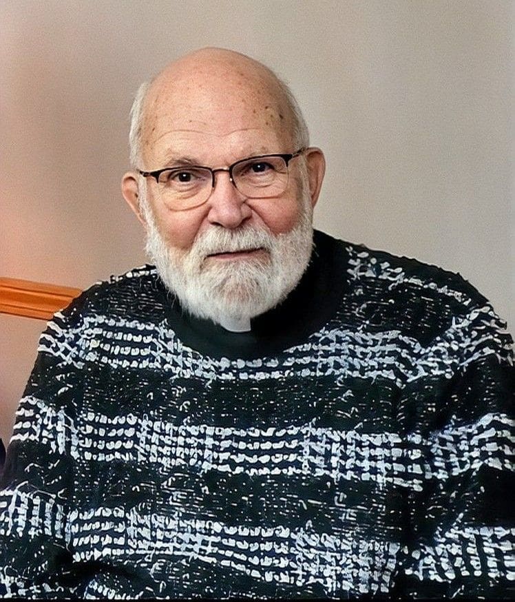 Elderly man with glasses and a patterned sweater.