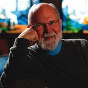 Elderly man smiling with colorful stained glass background.