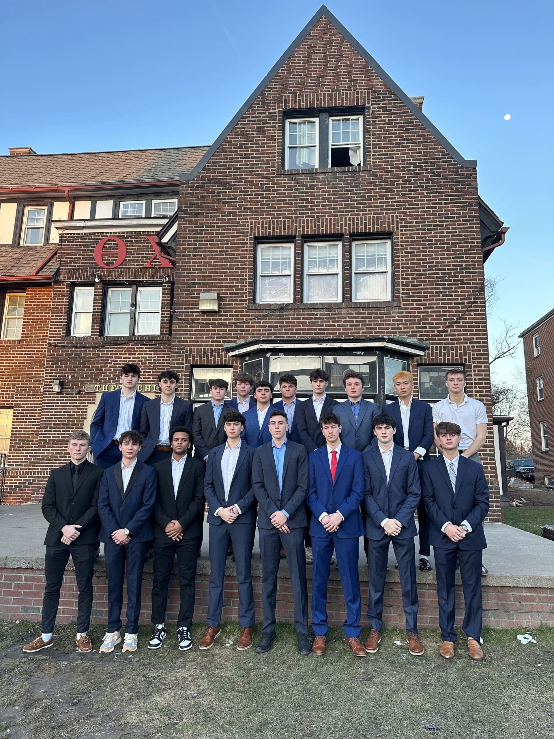Group of young men in suits outside a building.