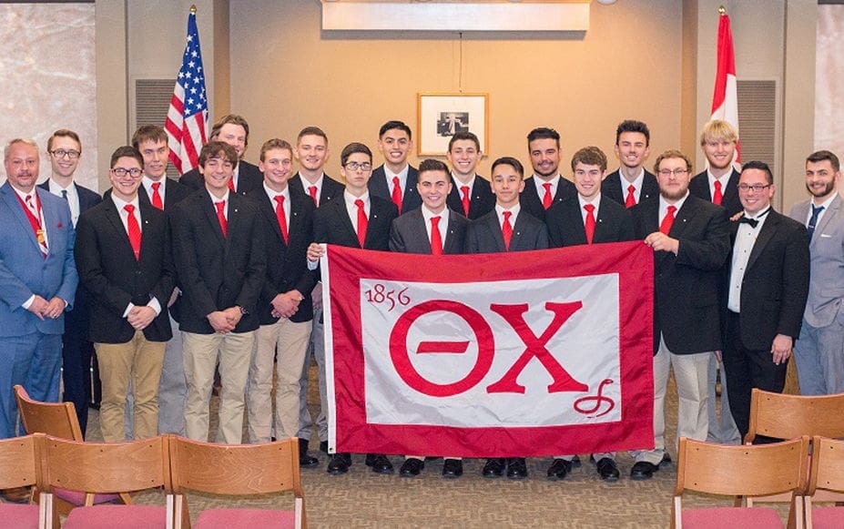 Group of fraternity members holding a flag.