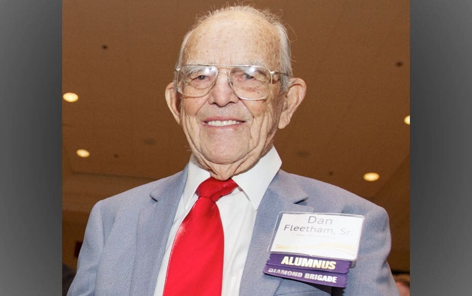 Smiling elderly man wearing glasses and suit.