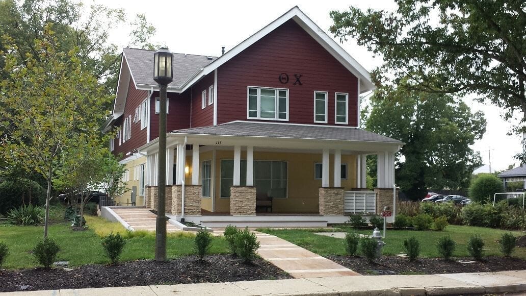 Modern red house with porch and landscaping.