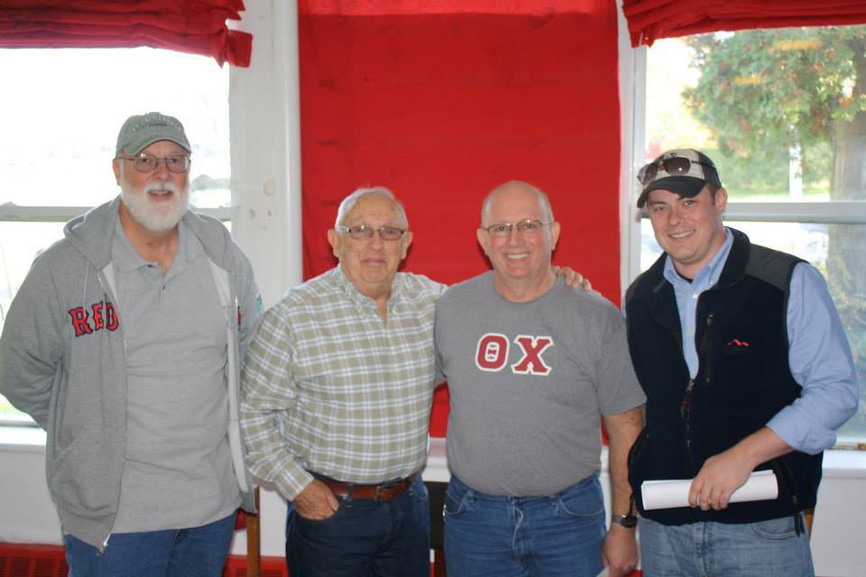 Group of four men smiling together indoors.