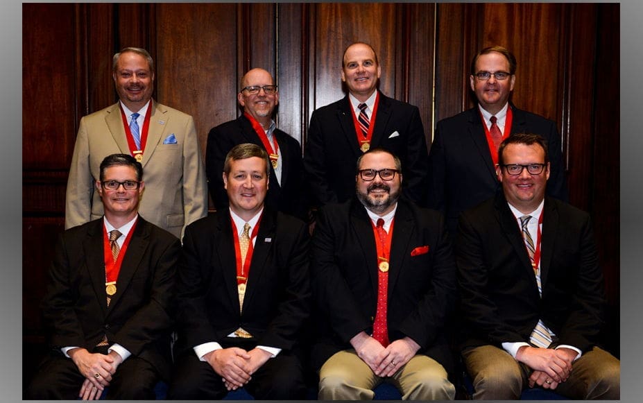 Group of men wearing medals, posing indoors.