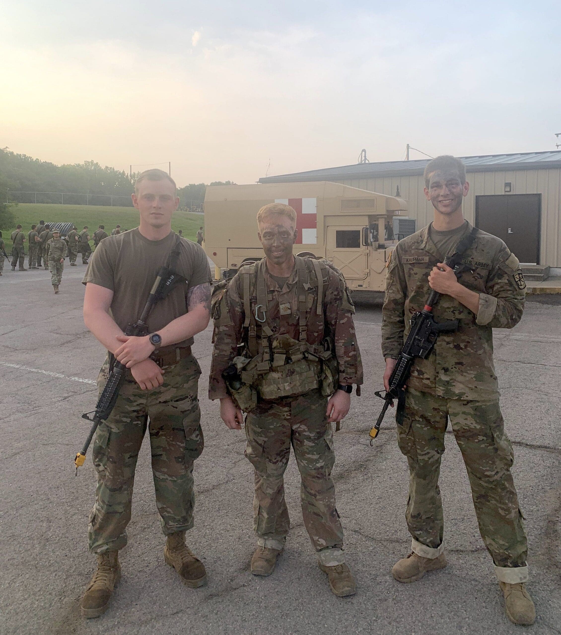 Gerron Elam Soldiers posing together with rifles outside military facility.