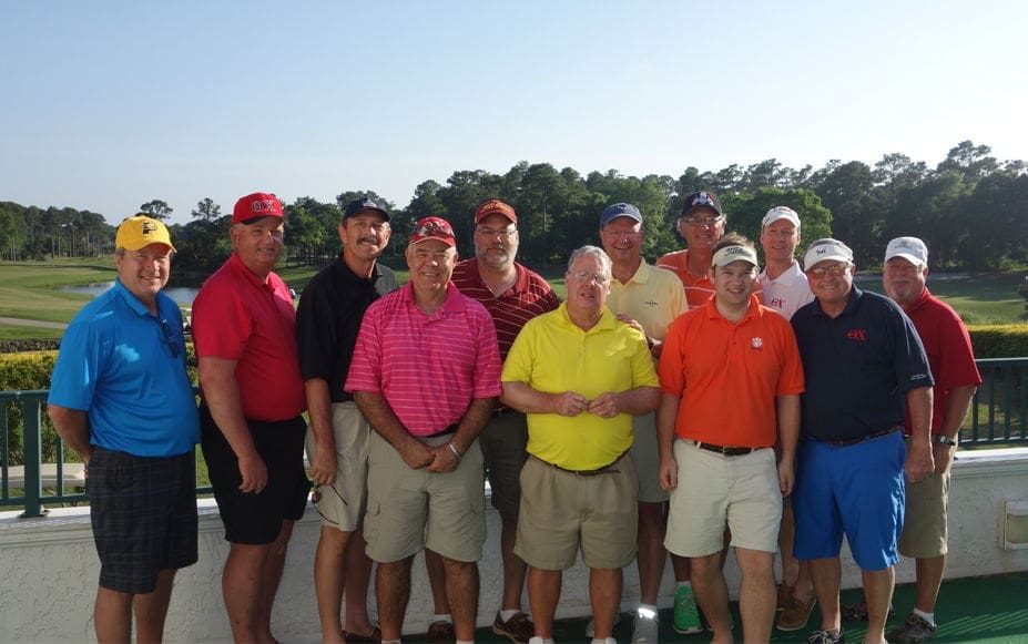 Golf group posing together outdoors on sunny day.