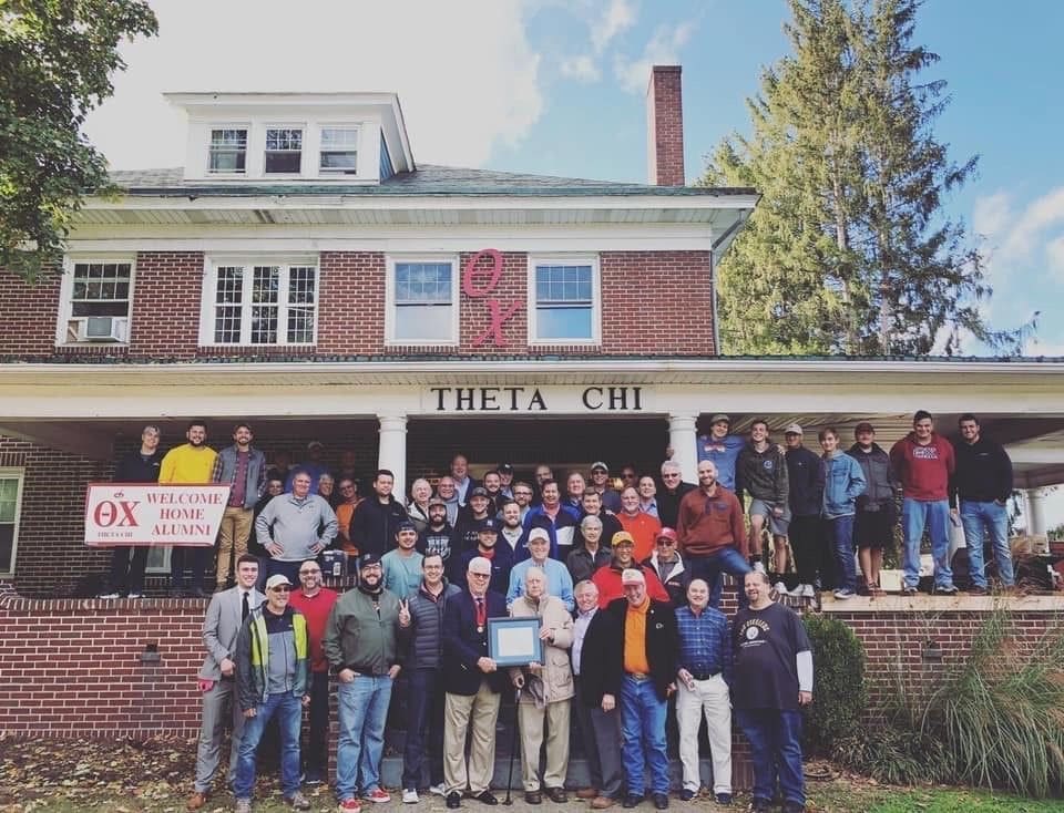 Graham Kenneweg Theta Chi fraternity reunion group photo outside house.
