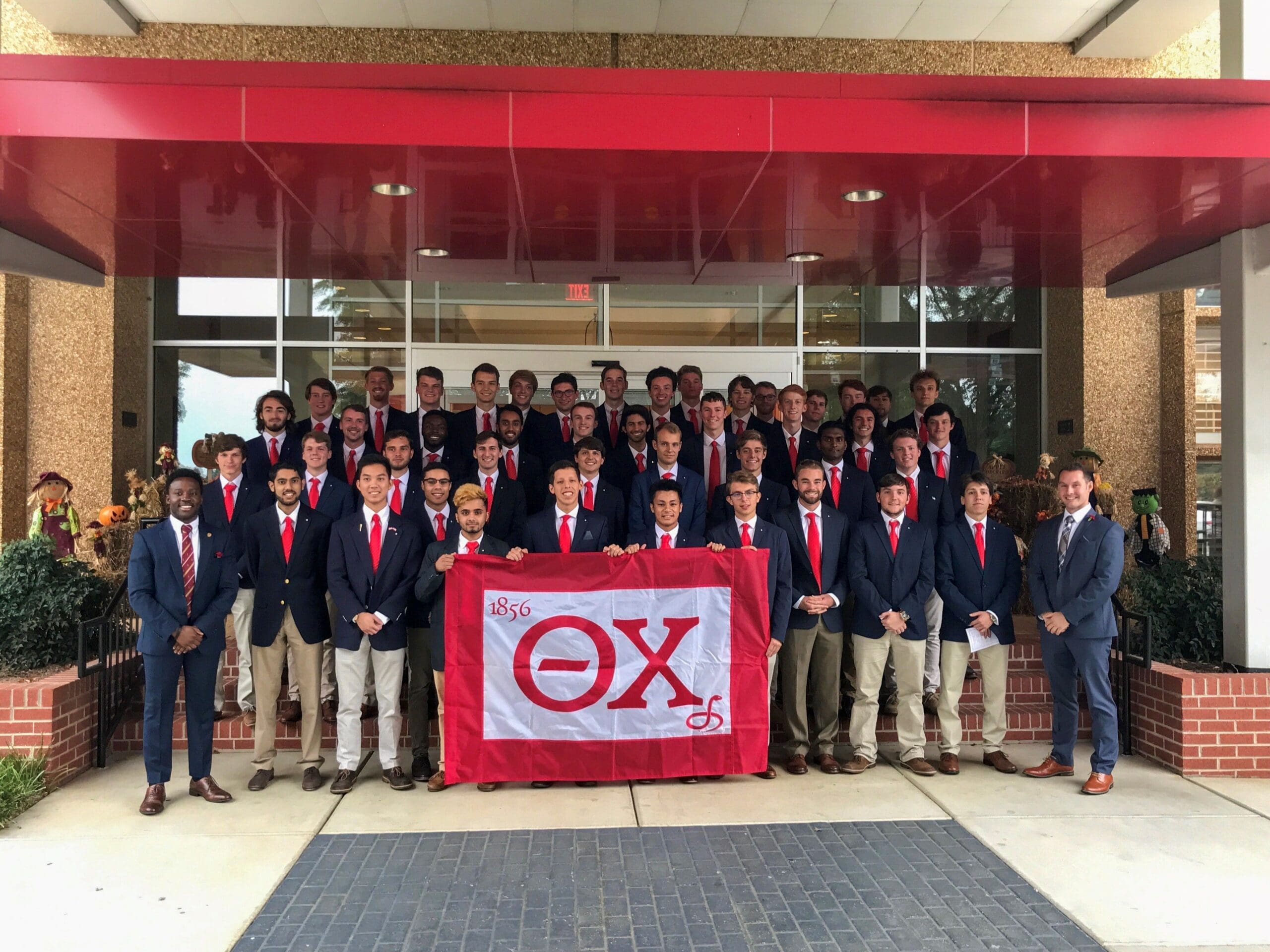 Group photo of fraternity members holding flag.