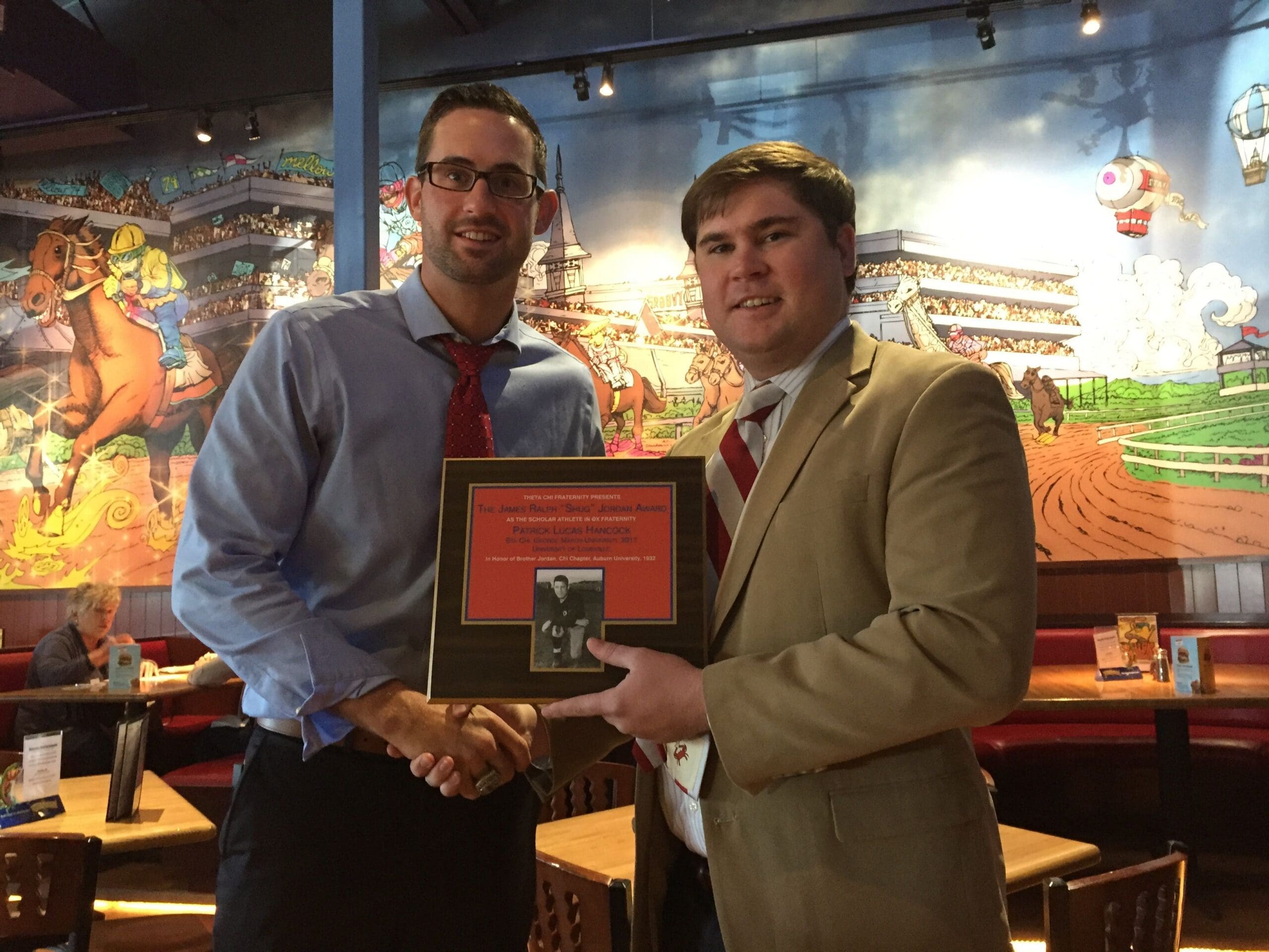 Two men exchanging an award in a restaurant.