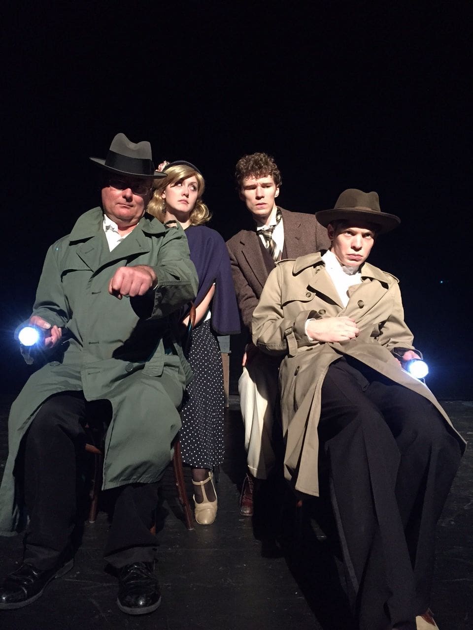 Theatrical performance featuring four actors with flashlights.