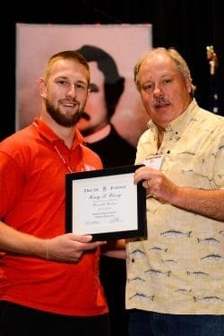 Two men presenting an award certificate at event.