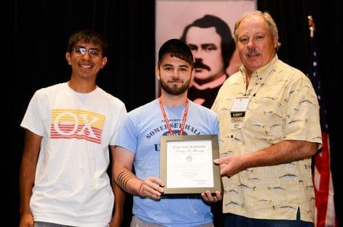 Award recipients holding certificate at ceremony event.