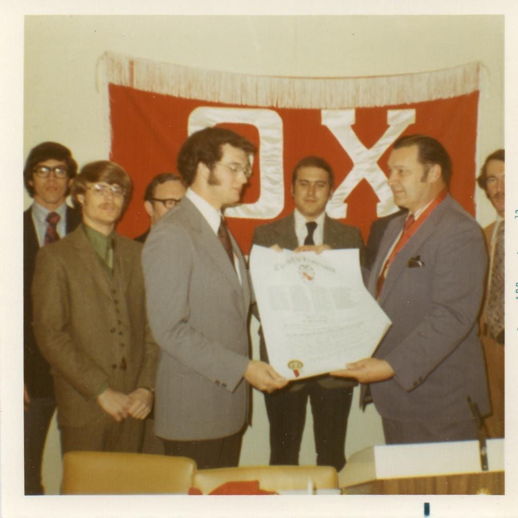 Eta Kappa - James Madison - Install Men in suits presenting a certificate under banner.