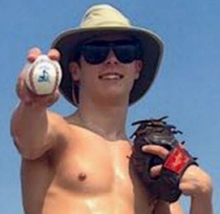 Young man in hat holding baseball and glove.