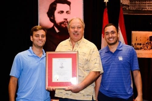 Three men celebrate an award presentation together.