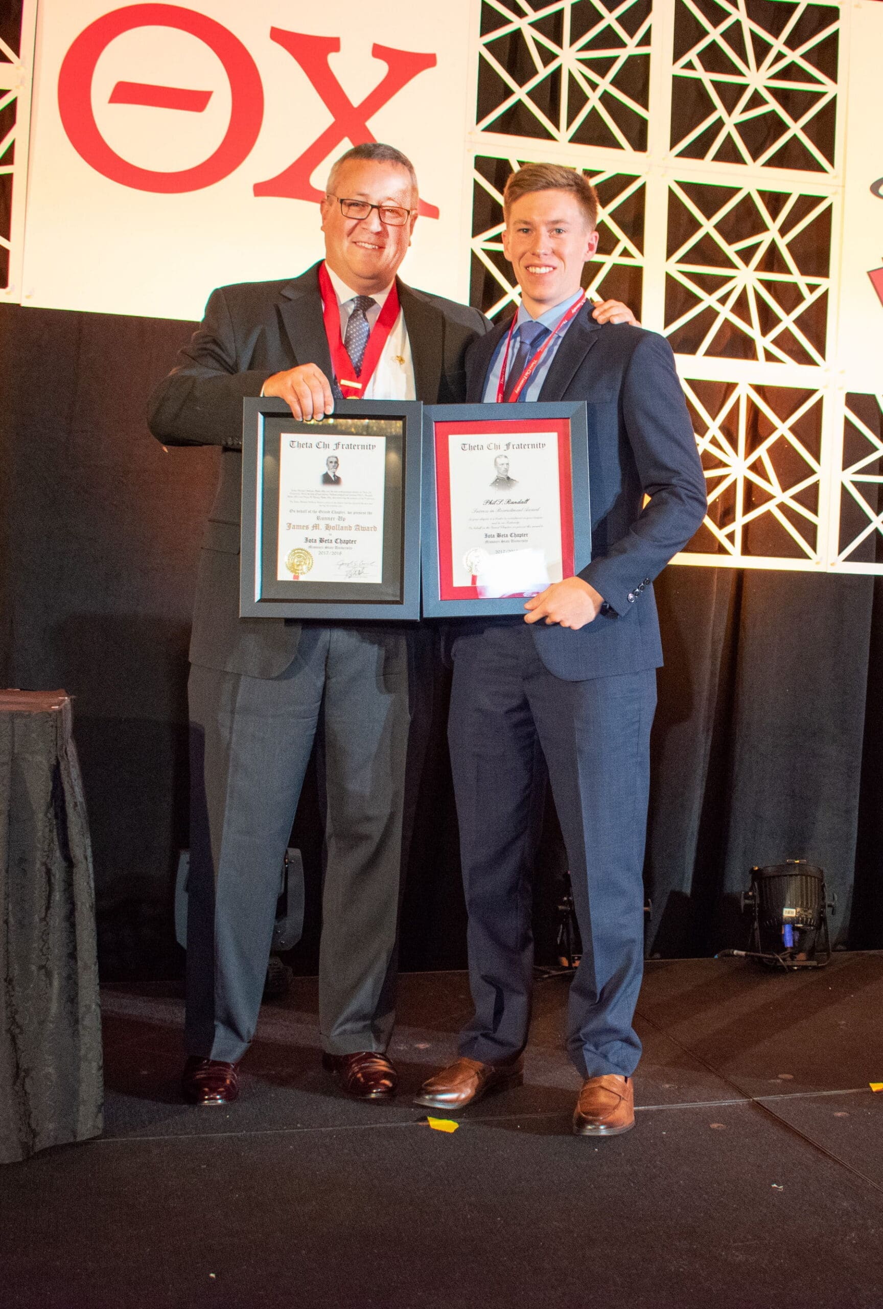 Two men holding awards at a formal event.