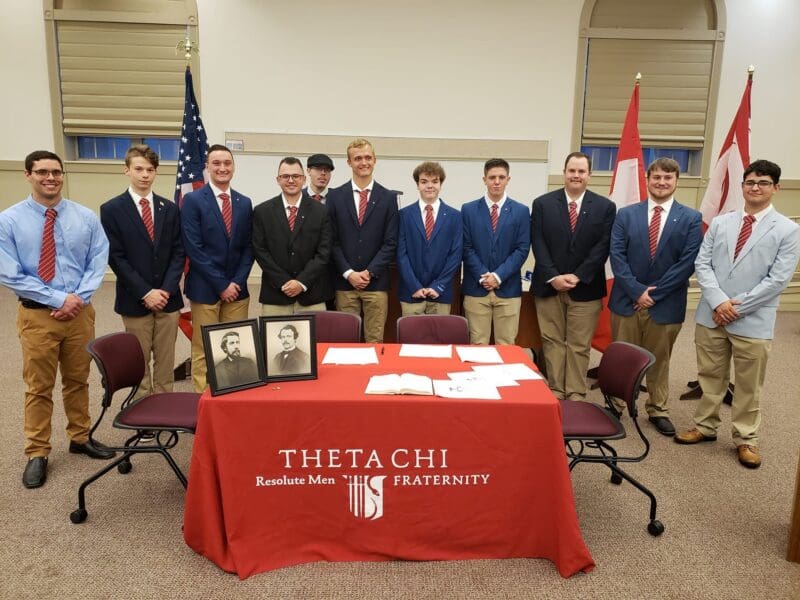 Theta Chi fraternity members at formal event gathering.