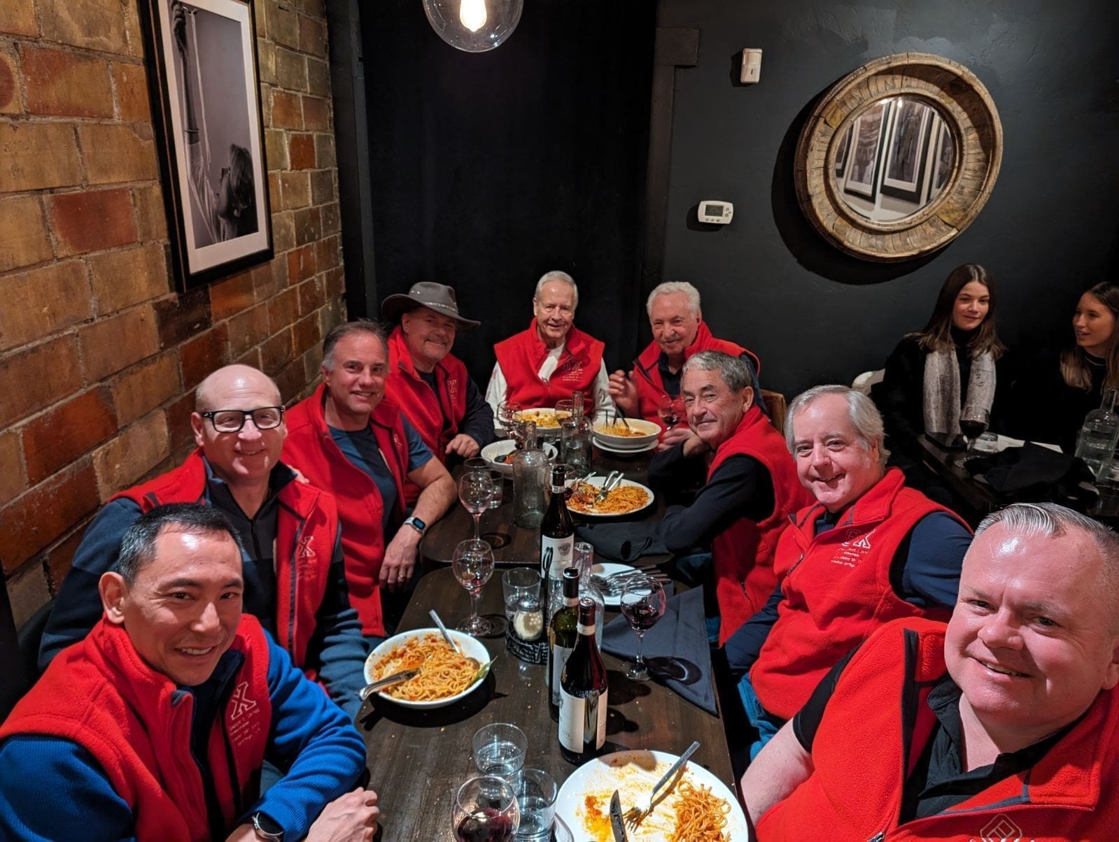 Group of friends dining in red vests.