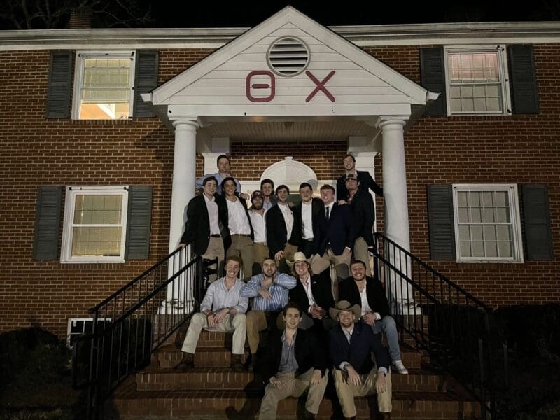 Group of fraternity members posing outside their house.