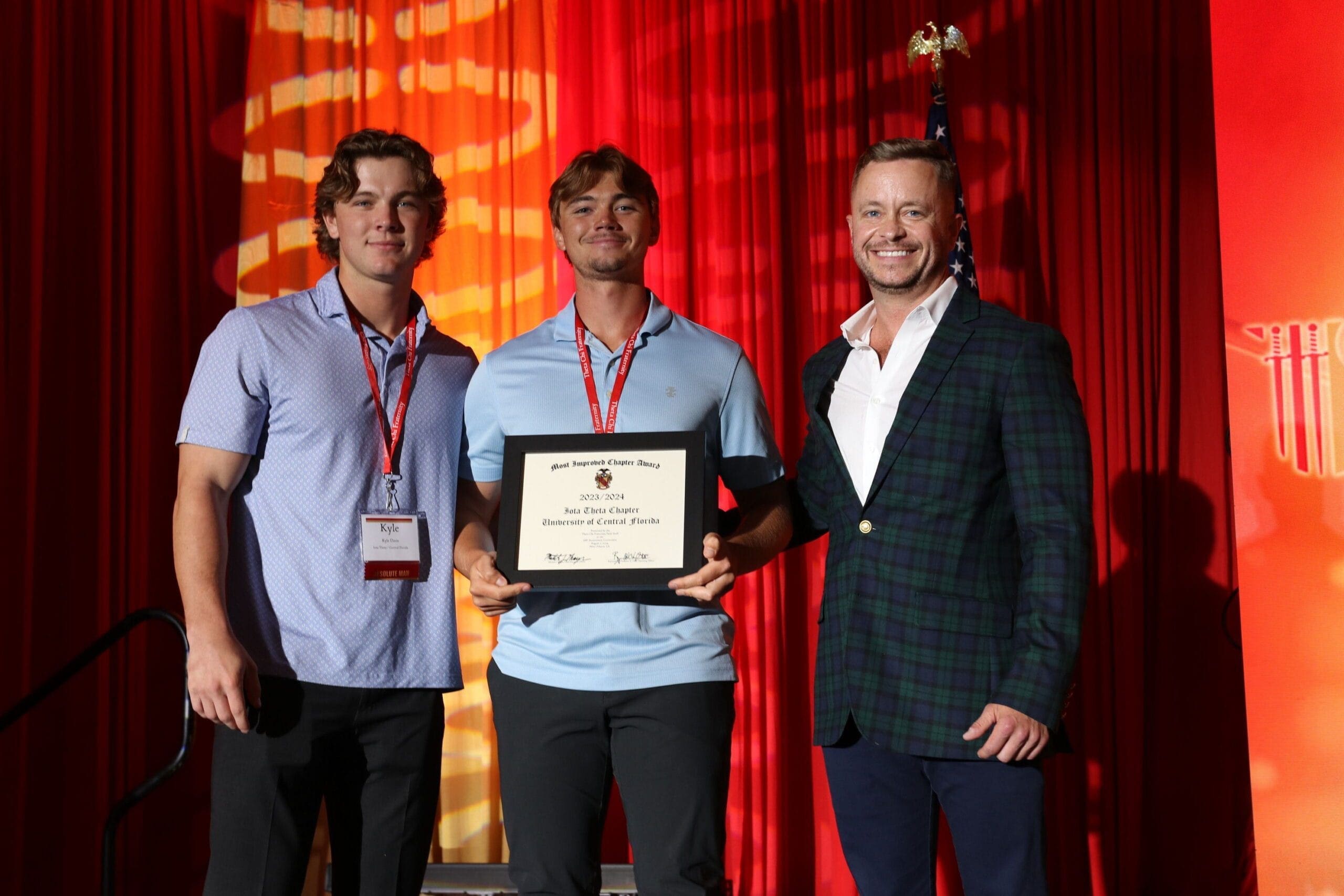 Three men at award ceremony holding certificate.