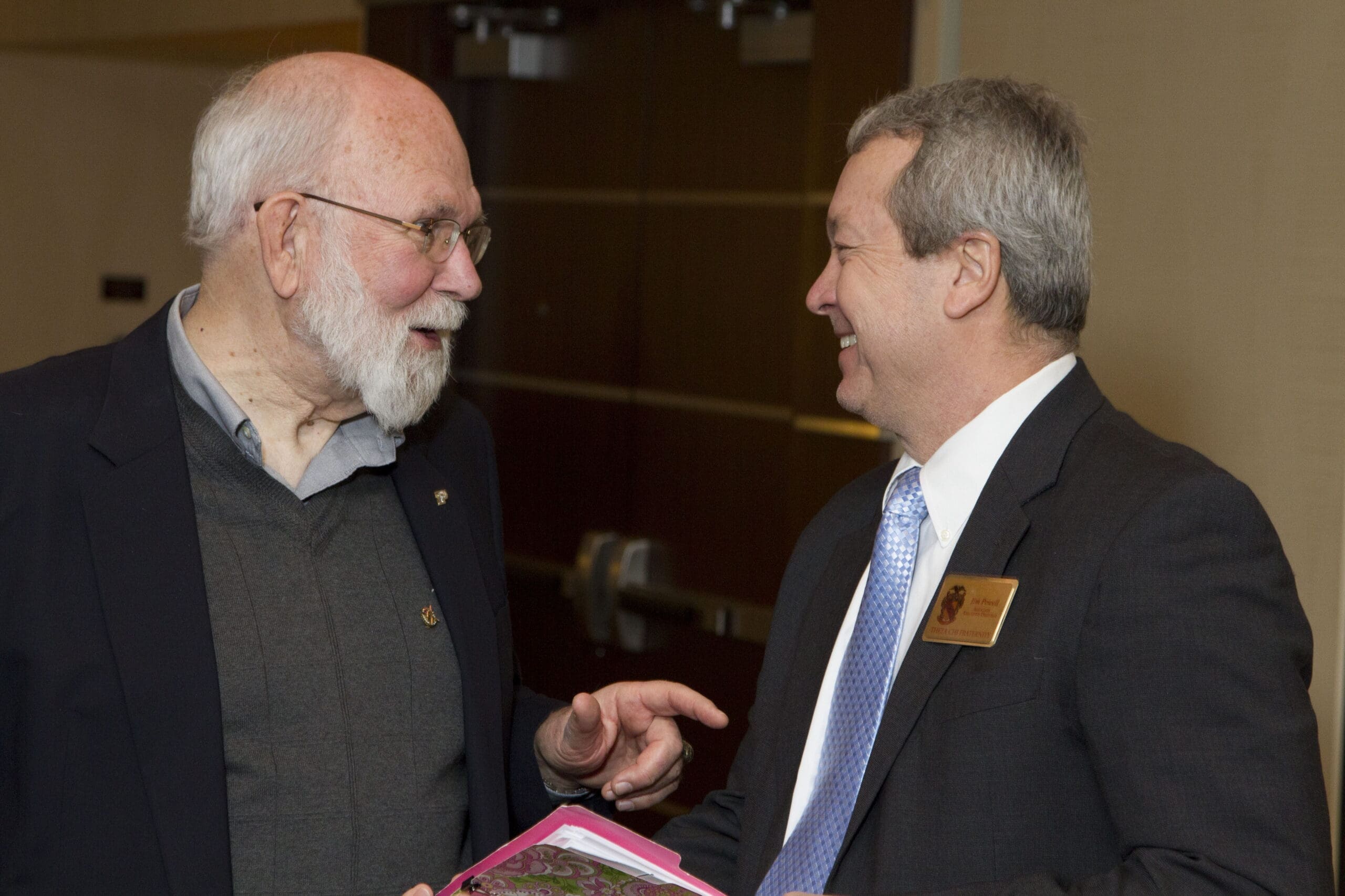 Two men engaged in a friendly conversation indoors.