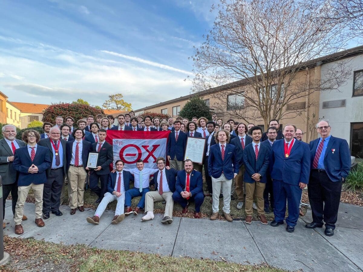Group photo of fraternity members with banner and awards.
