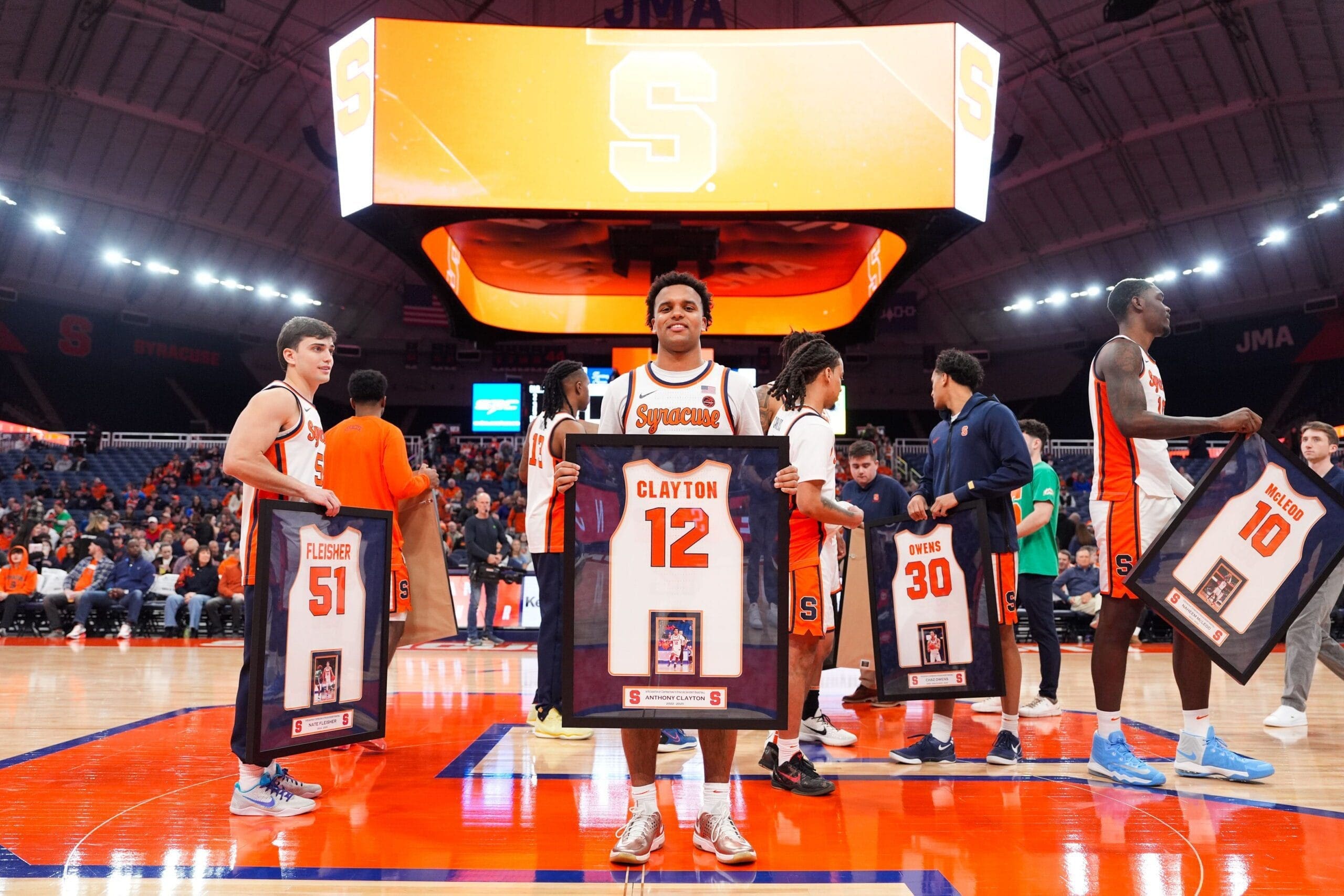 Syracuse basketball players honored with framed jerseys.