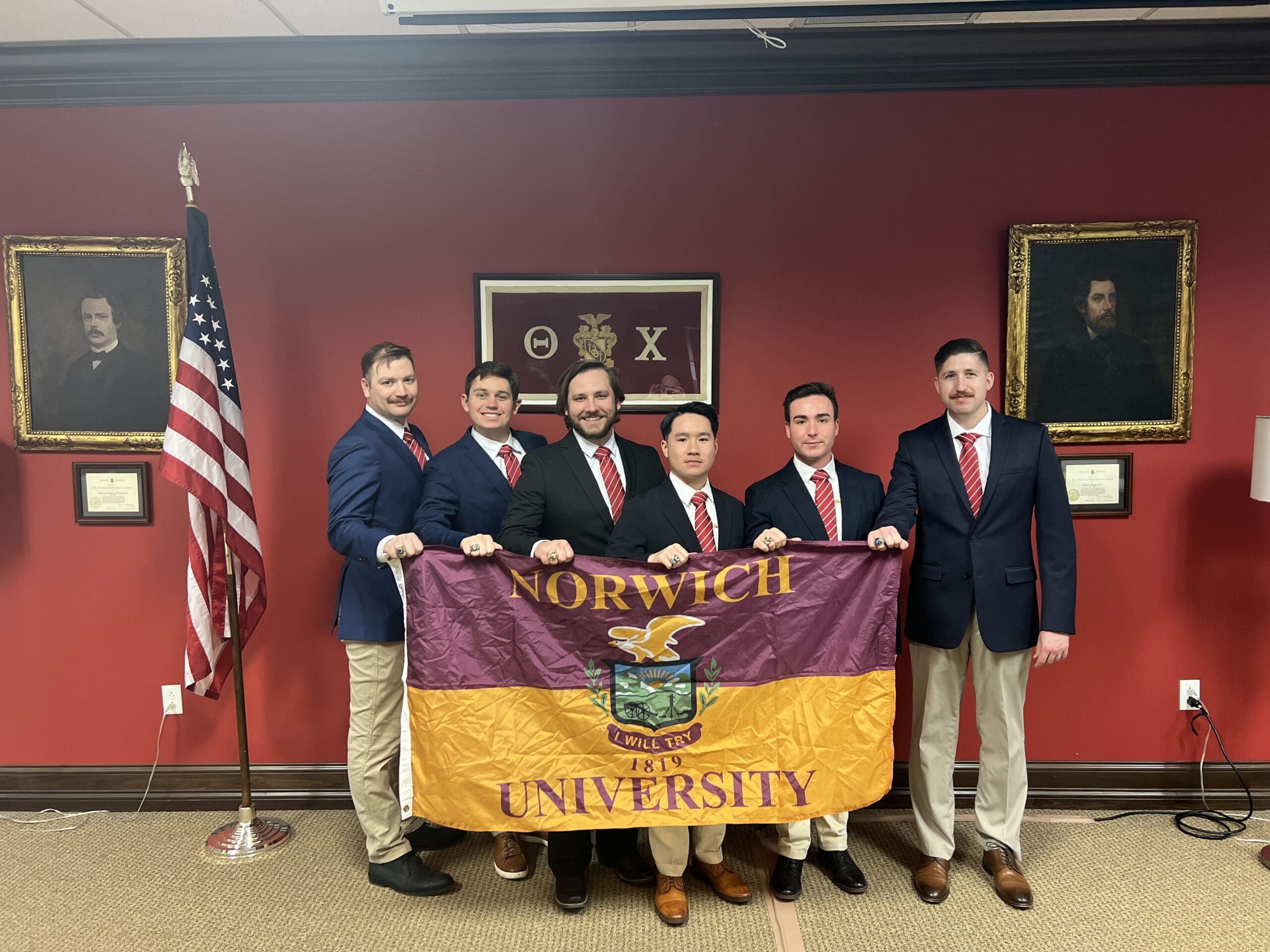Norwich University students holding school flag proudly.