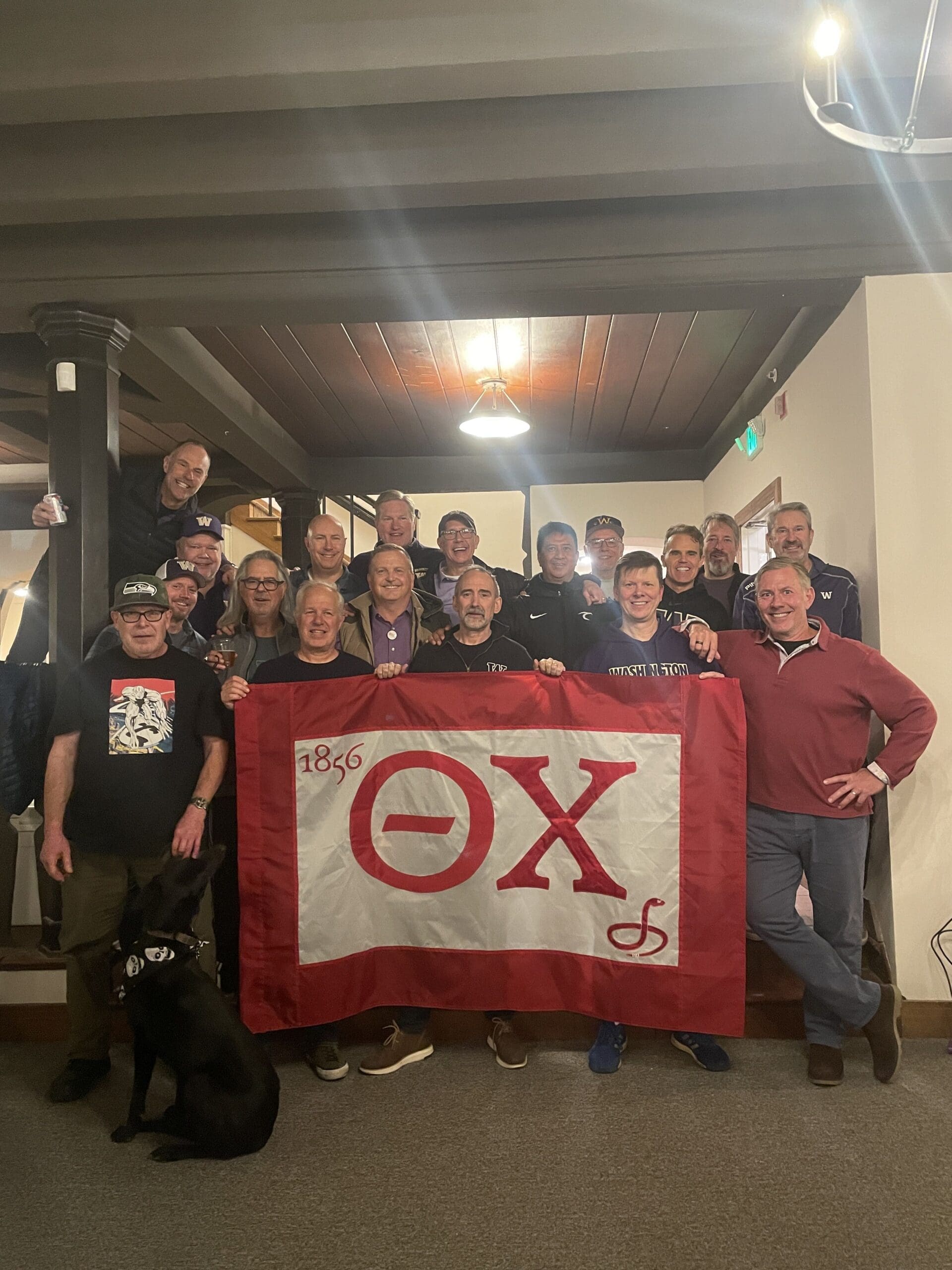 Group photo with Theta Chi fraternity members and flag.