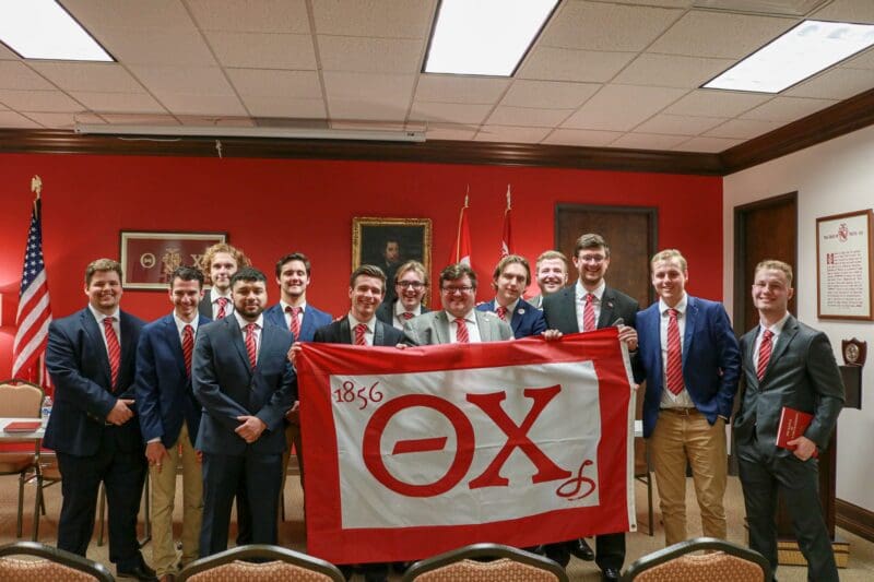 Group of fraternity members holding a flag.