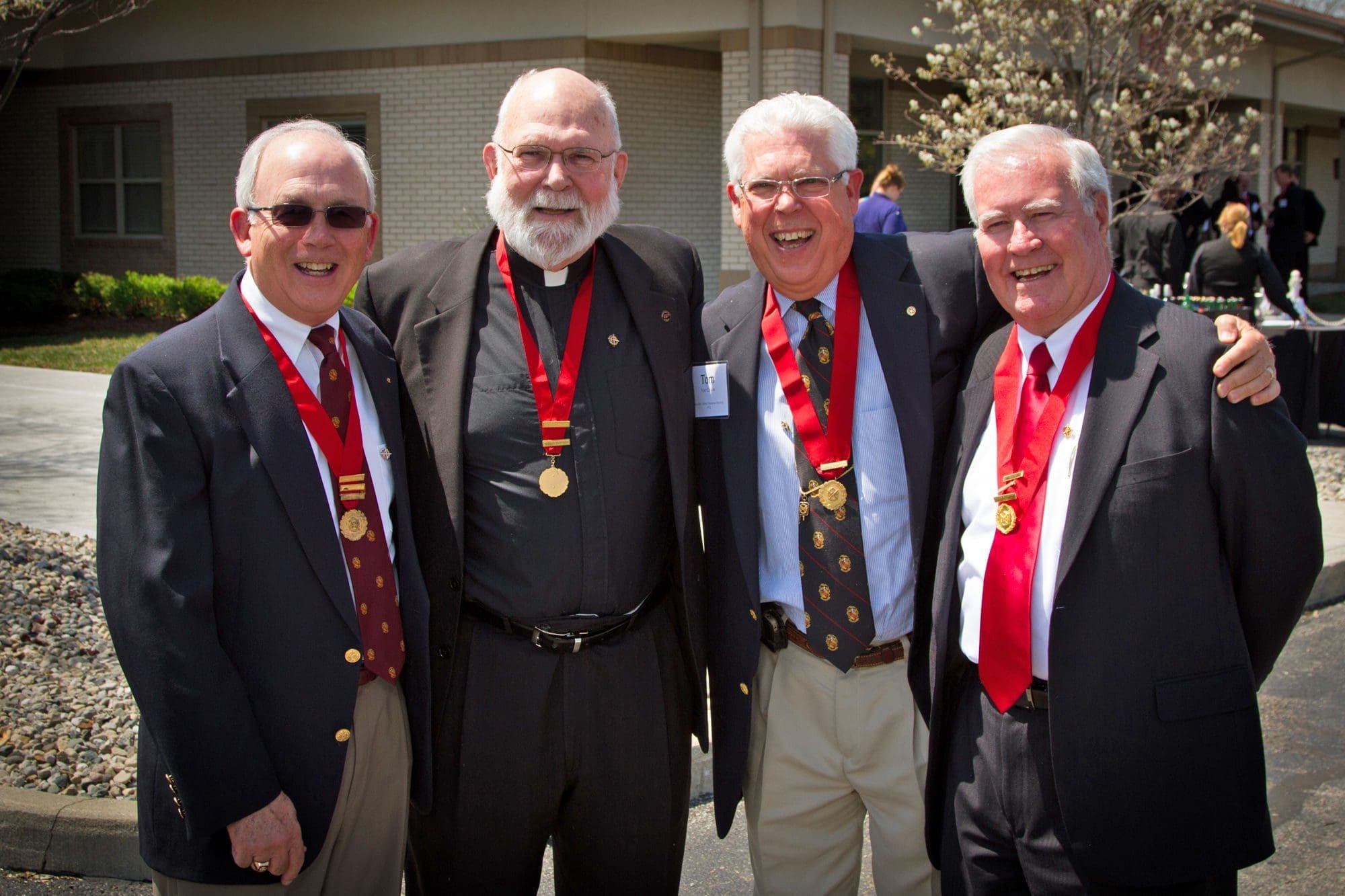 Four men in suits wearing medals and smiling.