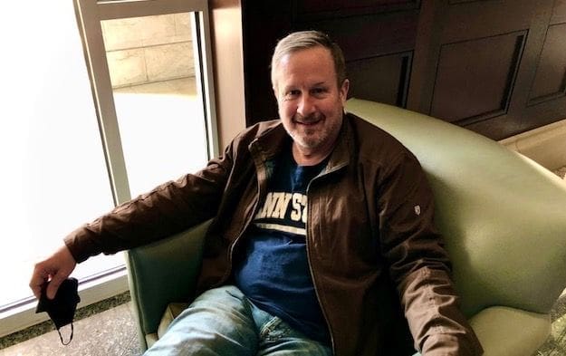Man sitting comfortably in a chair, smiling.